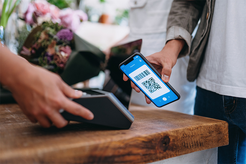 Customer holds their smartphone to digitally pay for a transaction at a store.